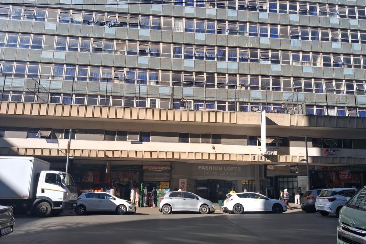 Street-level view of the Fashion Lofts apartment building, featuring a multi-story facade with ground-floor retail units and residential levels above.