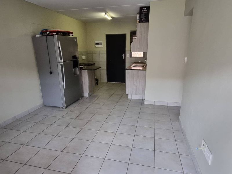 A functional kitchen area featuring tiled flooring, built-in cabinetry, and countertop space, providing a practical layout for daily meal preparation.