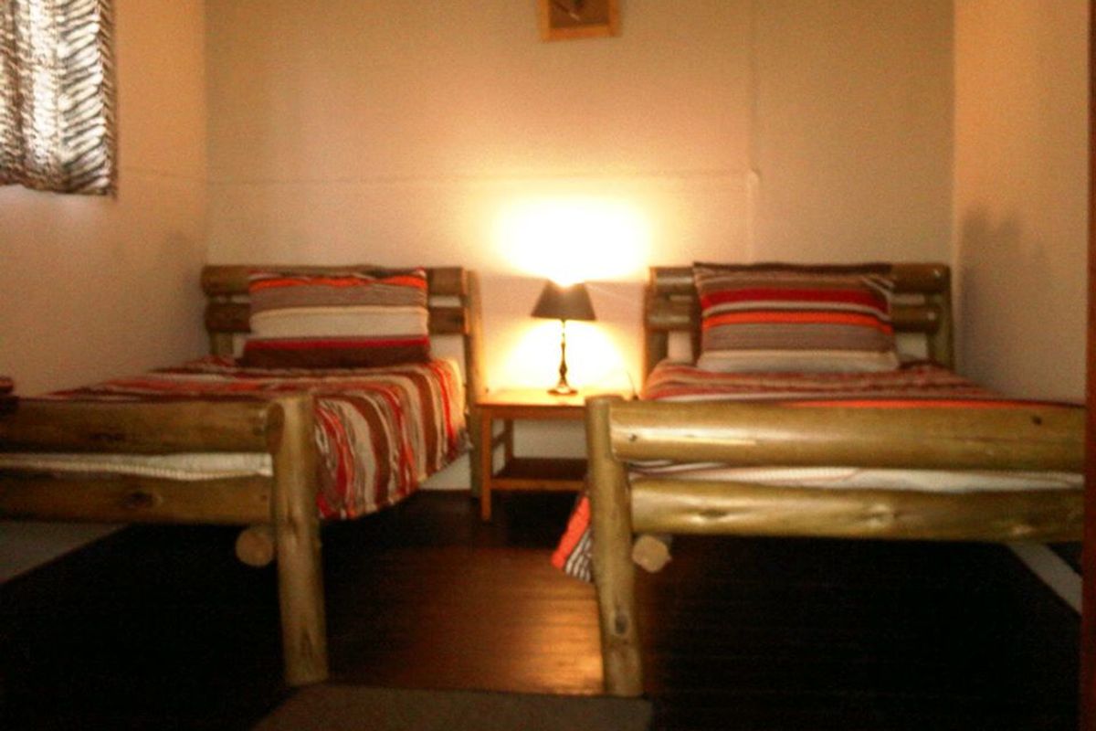 A rustic bedroom featuring dark wood flooring and two twin beds, providing a simple and functional sleeping space.