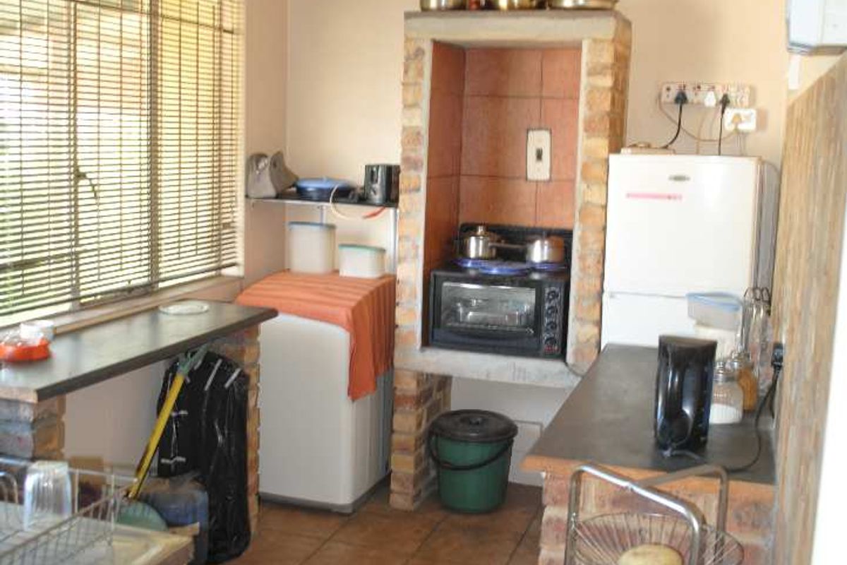 A functional kitchen area featuring brick-built cabinetry, tiled flooring, and a built-in stove alcove, offering a rustic and dated aesthetic.