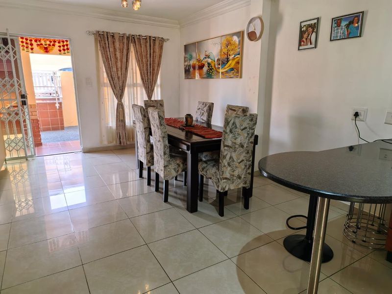 Open plan dining area featuring polished porcelain floor tiles, a breakfast bar, and direct access to an outdoor patio through a security gate.