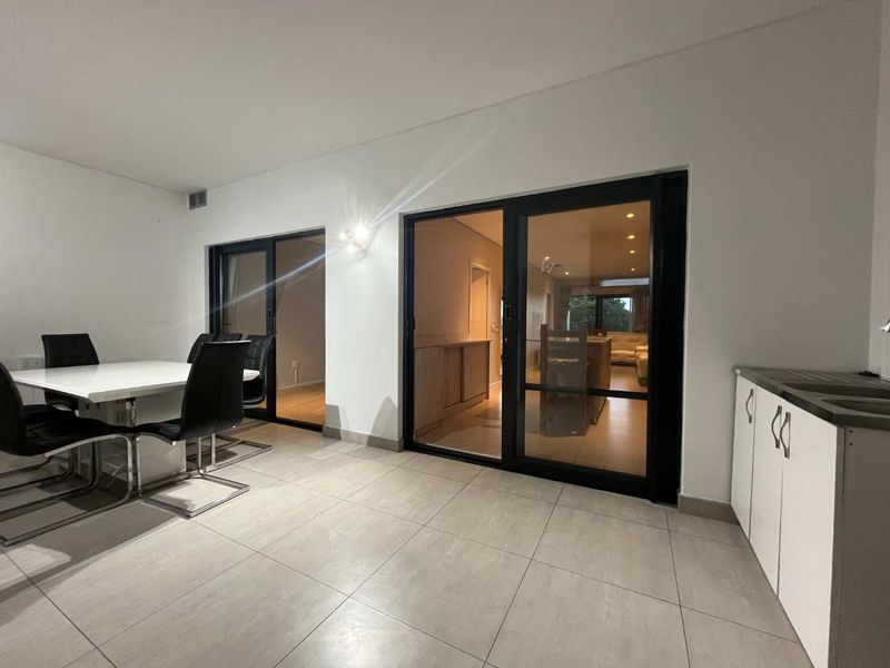 Open plan living and dining area featuring large sliding glass doors, neutral tiled flooring, and modern built-in kitchen cabinetry.
