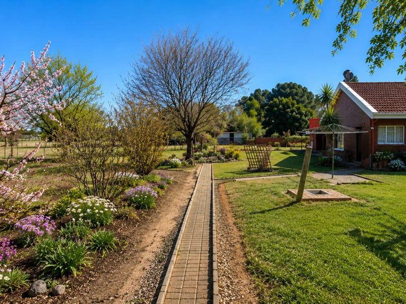 A well-maintained garden featuring a brick paved pathway, lush lawn, and established landscaping alongside the brick residential building.