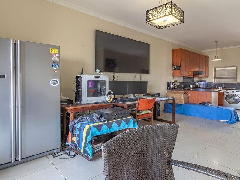 Open-plan living and kitchen area featuring tiled flooring, wooden cabinetry, and access to an outdoor balcony.
