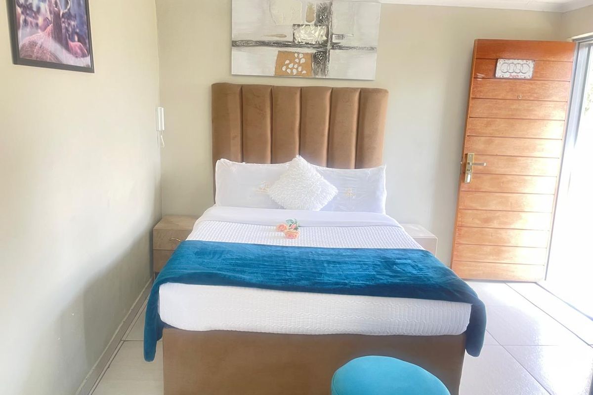 A well-maintained bedroom featuring tiled flooring and a wooden entrance door, providing a clean and functional space for guests.