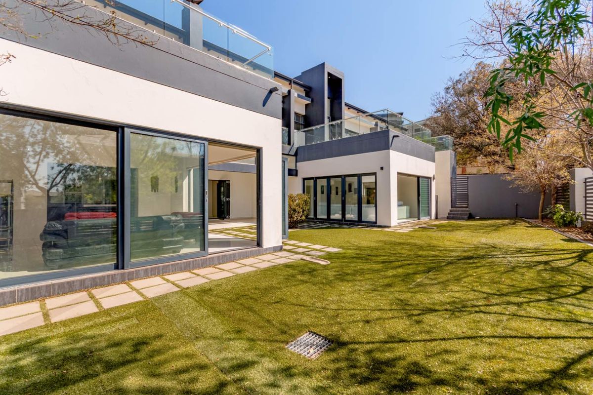 Modern rear exterior view featuring a landscaped lawn, paved pathways, and large sliding glass doors leading into the home's living spaces.