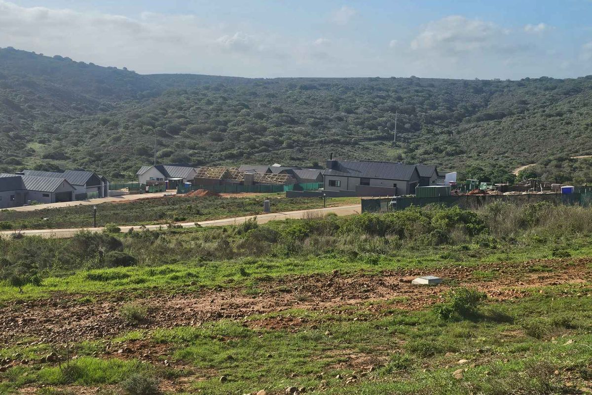 An elevated view of a residential development under construction, featuring modern homes set against a natural hillside landscape.