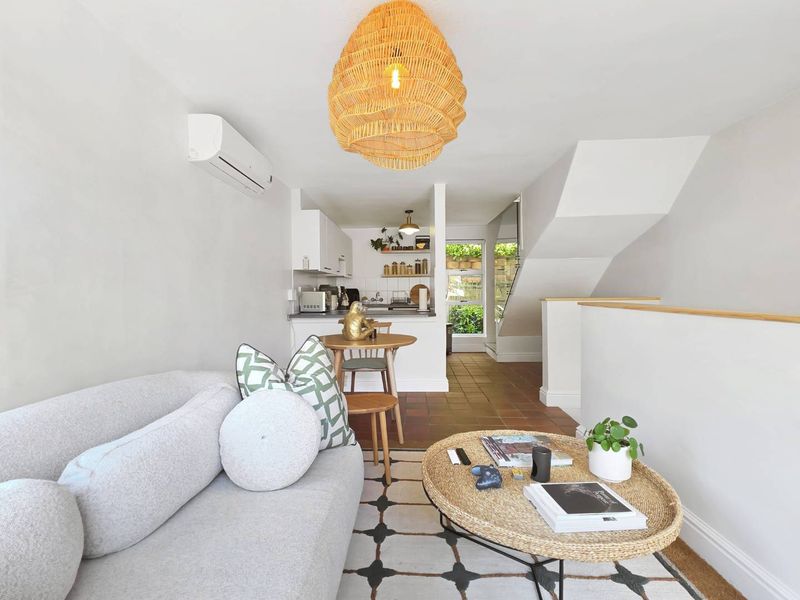 Open-plan living and kitchen area featuring tiled flooring, a split-system air conditioner, and a staircase leading to the upper level.