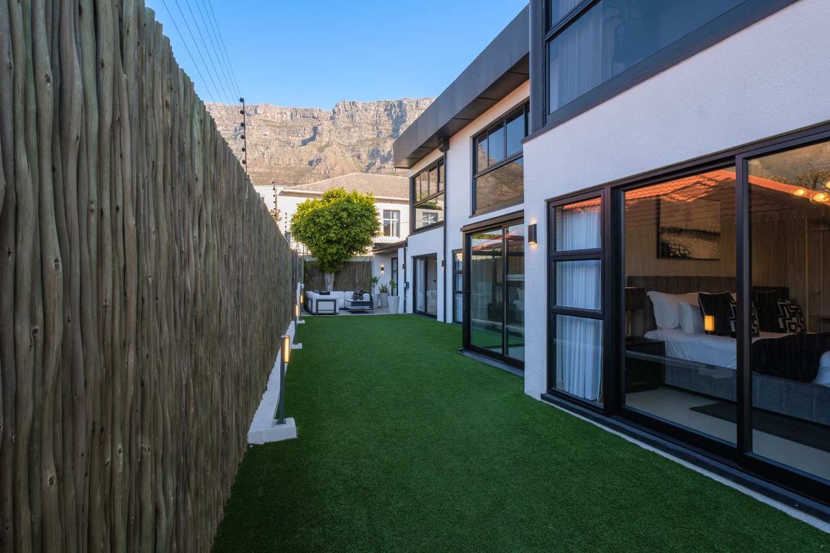 A well-maintained rear garden area featuring artificial turf, a timber pole boundary fence, and modern sliding glass doors leading into the home.