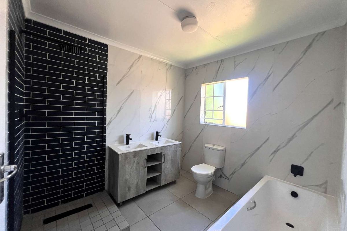 Modern bathroom featuring a double vanity, walk-in shower with black subway tiles, a bathtub, and marble-effect wall tiling.