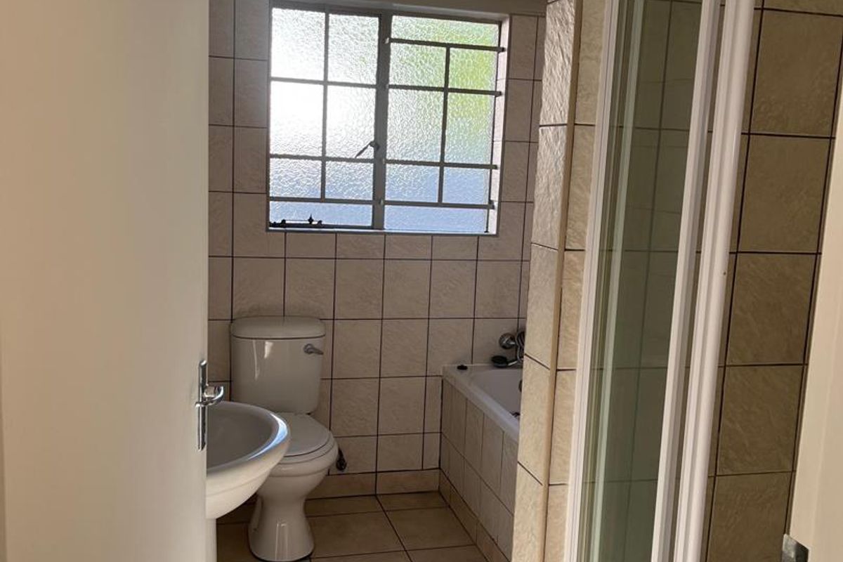 A functional bathroom featuring a pedestal basin, a toilet, a built-in bathtub, and a separate shower enclosure with tiled walls and flooring.