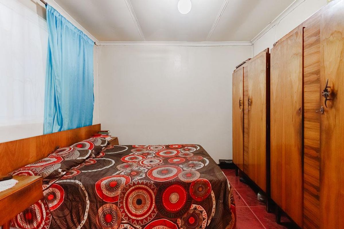A functional bedroom featuring built-in wooden wardrobes and tiled flooring, offering a practical layout for comfortable living.