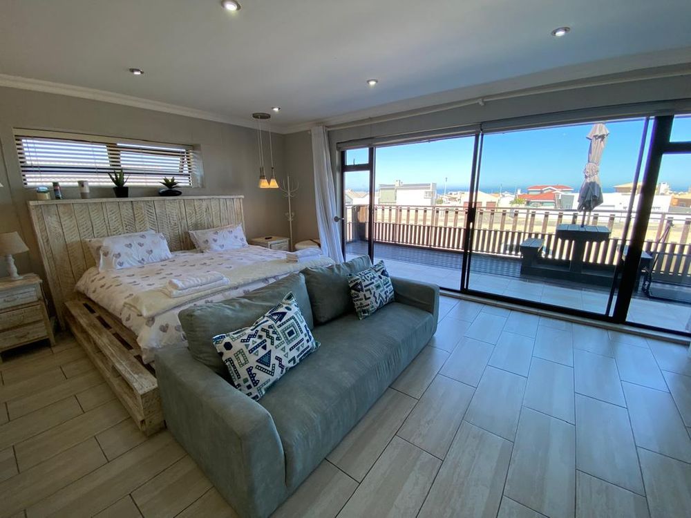First-floor main bedroom with built-in cupboards and en-suite bathroom. It also has a balcony with distant sea views