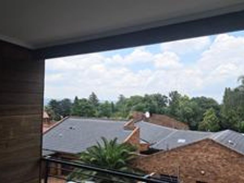 A covered balcony featuring timber wall cladding and a metal balustrade, offering an elevated view over the surrounding residential area.