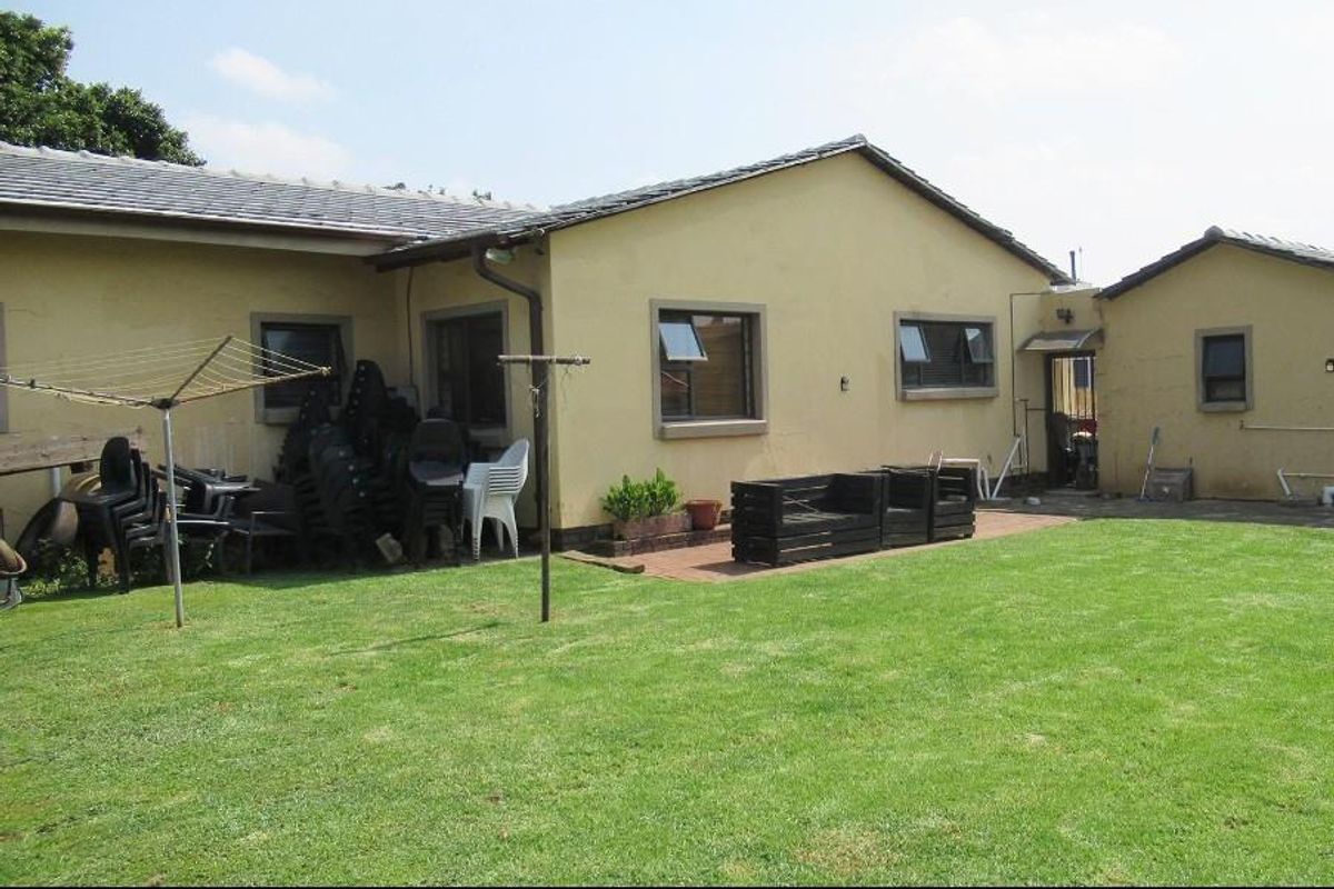 Rear view of the house featuring a paved patio area, lawn, and exterior wall finishes.
