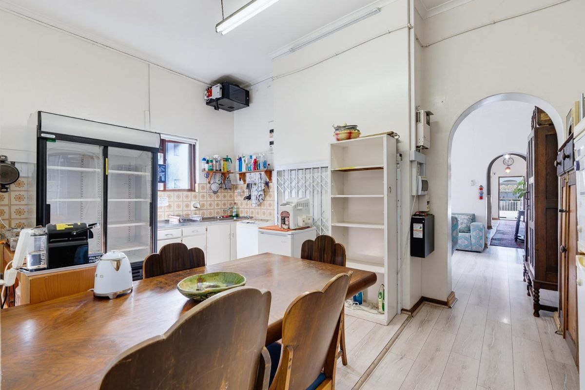 A dated kitchen area featuring original cabinetry, tiled splashbacks, and an arched doorway leading to the adjacent living space.