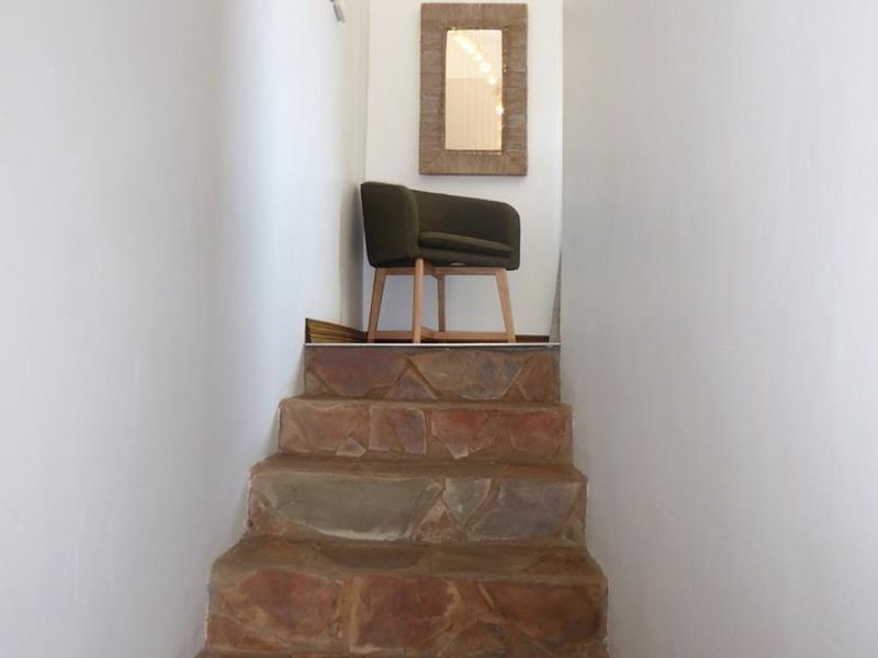 A narrow interior hallway featuring a rustic stone staircase leading to an upper level.