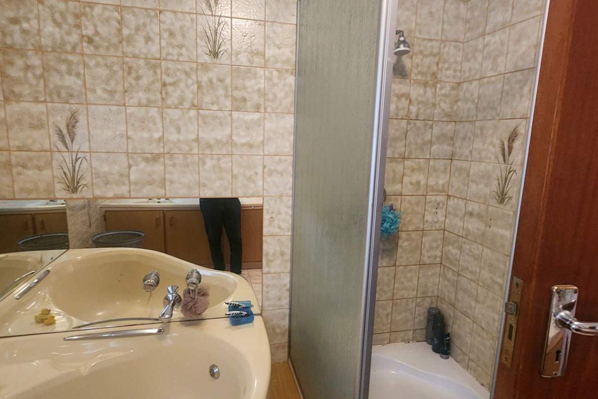 A dated bathroom featuring a corner bathtub, a separate shower enclosure, and a built-in vanity with a large mirror.