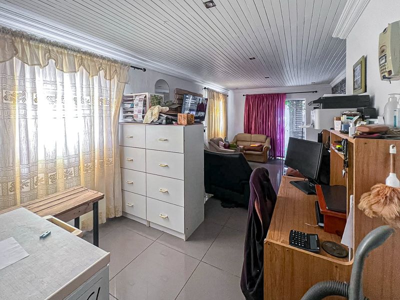 A spacious living area featuring tiled flooring, a tongue and groove ceiling with recessed lighting, and direct access to the outdoor area via sliding doors.
