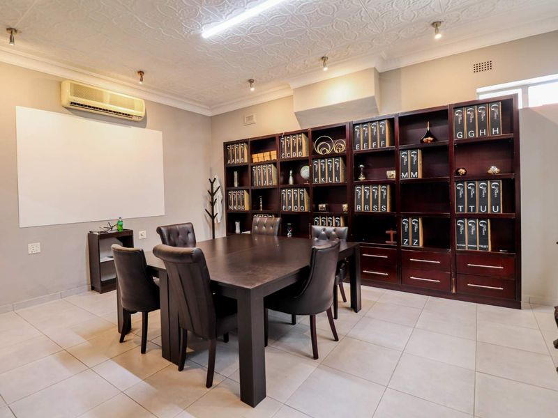 A professional office space featuring built-in dark wood cabinetry, tiled flooring, and a mounted air conditioning unit.