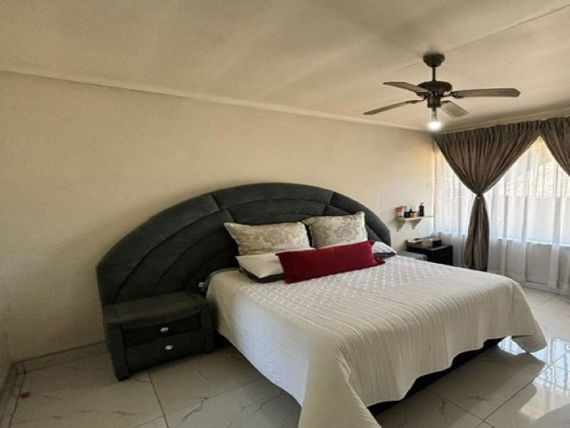 A spacious bedroom featuring tiled flooring and a ceiling fan, offering a neutral canvas for personalization.