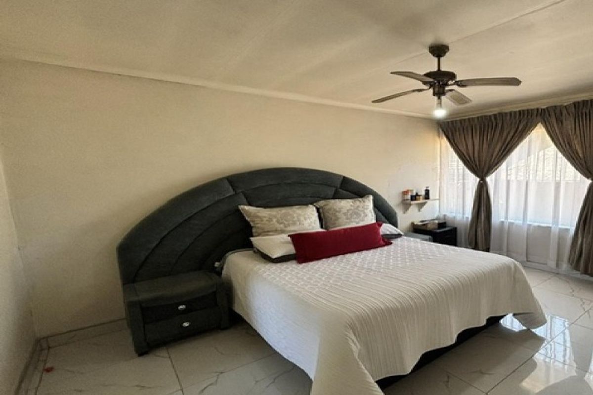 A spacious bedroom featuring tiled flooring and a ceiling fan, offering a neutral canvas for personalization.