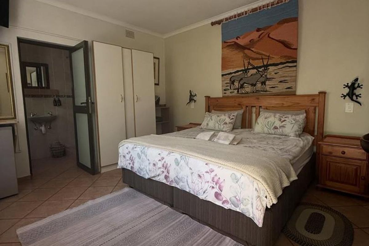 A bedroom featuring tiled flooring, built-in cupboards, and an en-suite bathroom access.