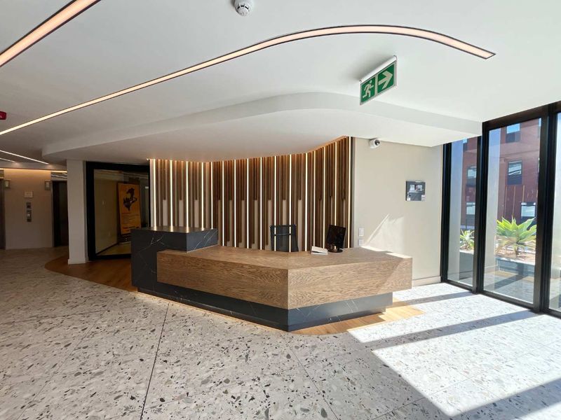 Modern office reception area featuring a custom built-in desk, elegant terrazzo flooring, and decorative slatted timber wall paneling with integrated lighting.