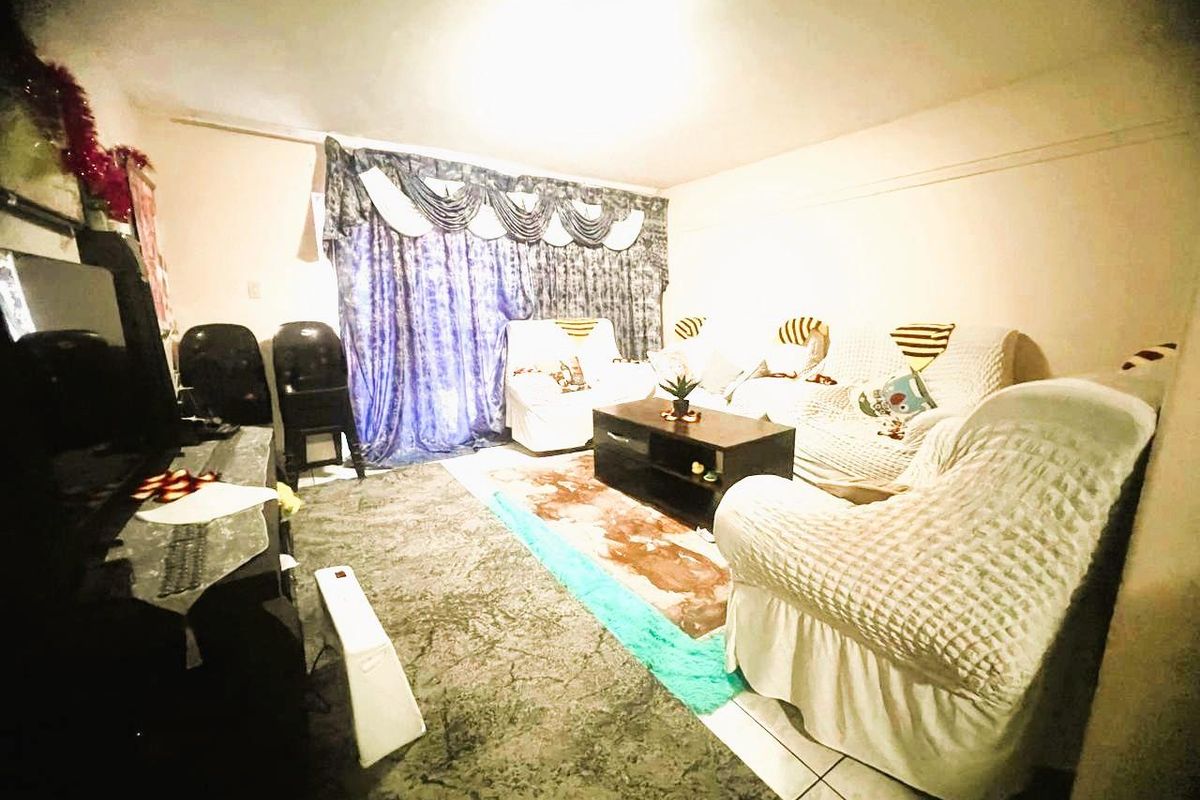 A living room area featuring tiled flooring and window treatments, requiring cosmetic updates to improve the overall aesthetic and condition of the space.
