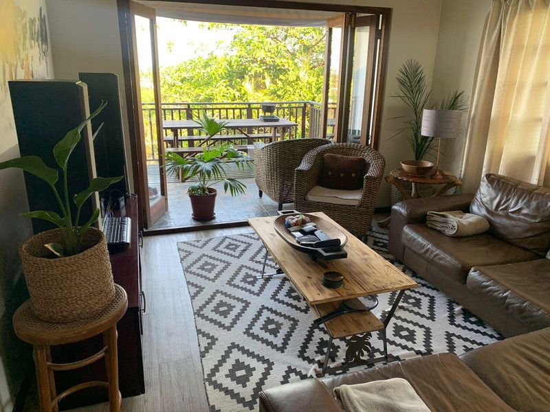 A comfortable living room featuring laminate flooring and double french doors that open onto a private balcony, providing natural light and outdoor flow.