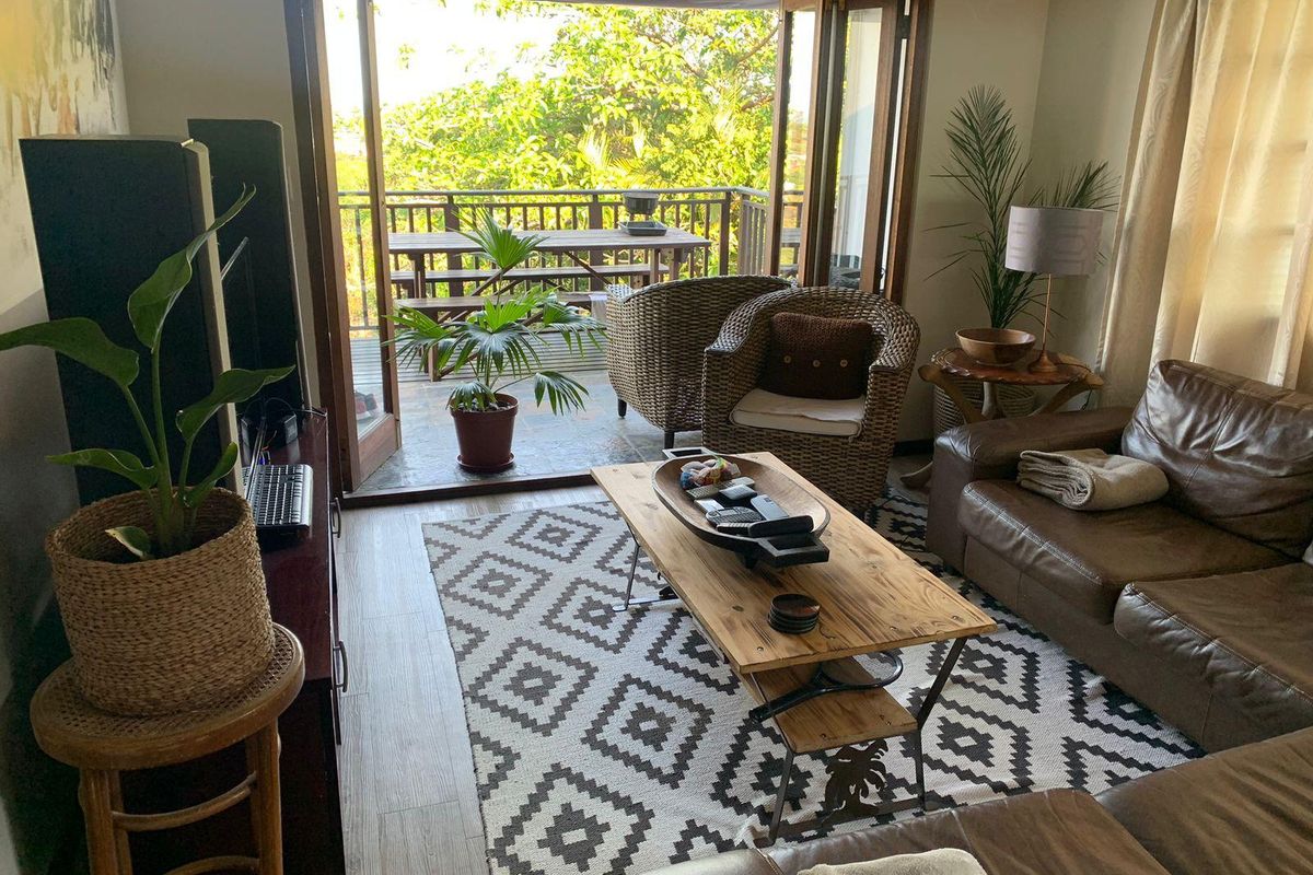 A comfortable living room featuring laminate flooring and double french doors that open onto a private balcony, providing natural light and outdoor flow.