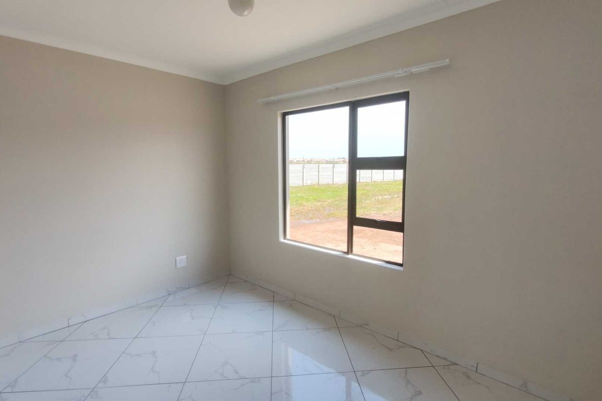 A bright, empty bedroom featuring modern white marble-look floor tiles, neutral wall paint, and a large window with dark frames.