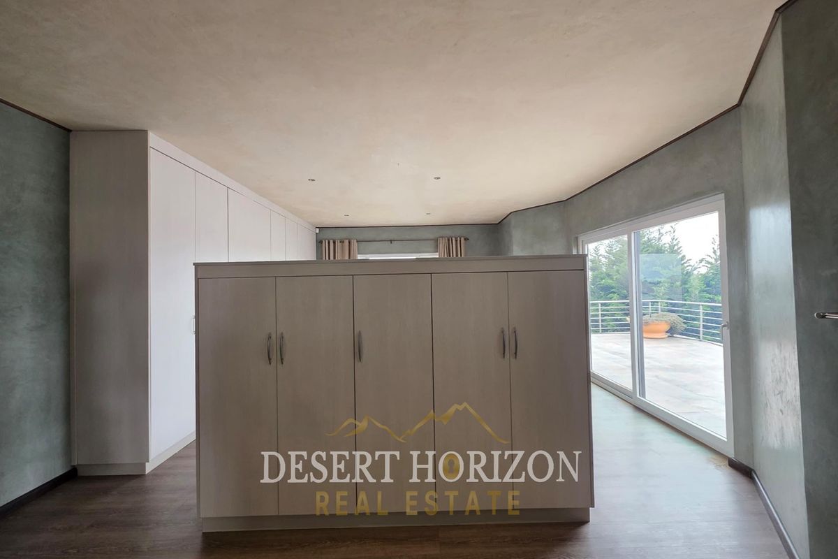 Spacious bedroom featuring extensive built-in cabinetry, modern laminate flooring, and large sliding glass doors opening to an outdoor balcony area.