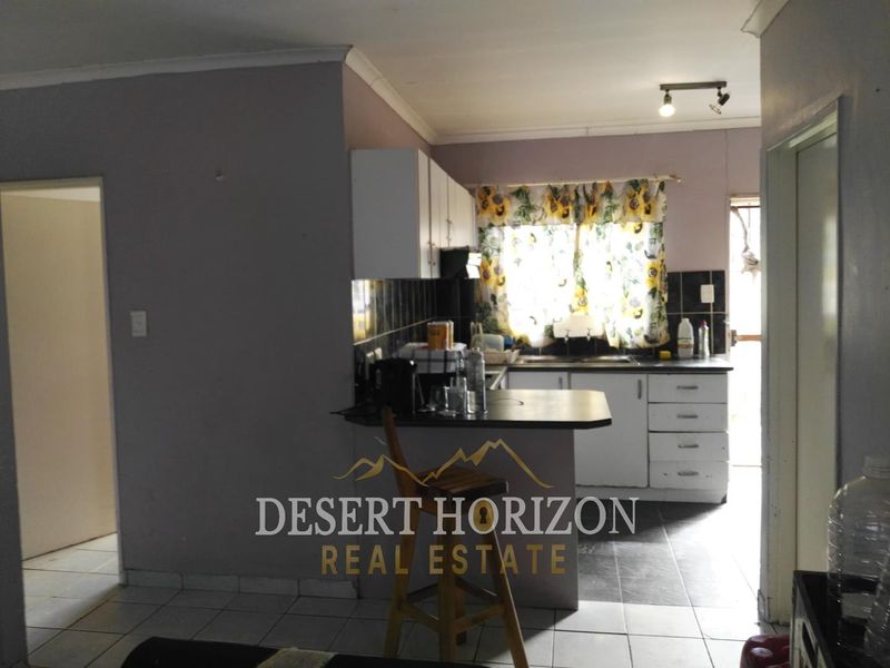 A functional kitchen featuring built-in cabinetry, tiled flooring, and a breakfast counter, offering potential for modernization and aesthetic updates.