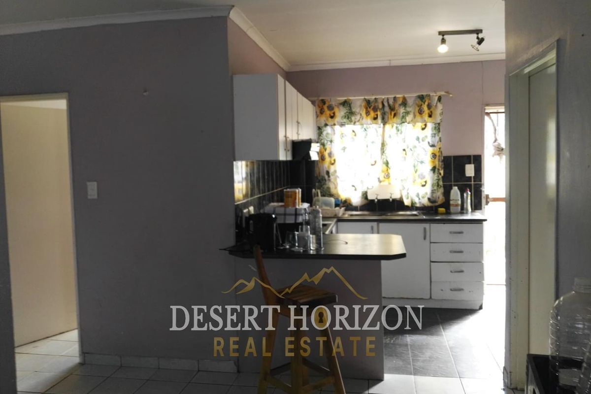 A functional kitchen featuring built-in cabinetry, tiled flooring, and a breakfast counter, offering potential for modernization and aesthetic updates.