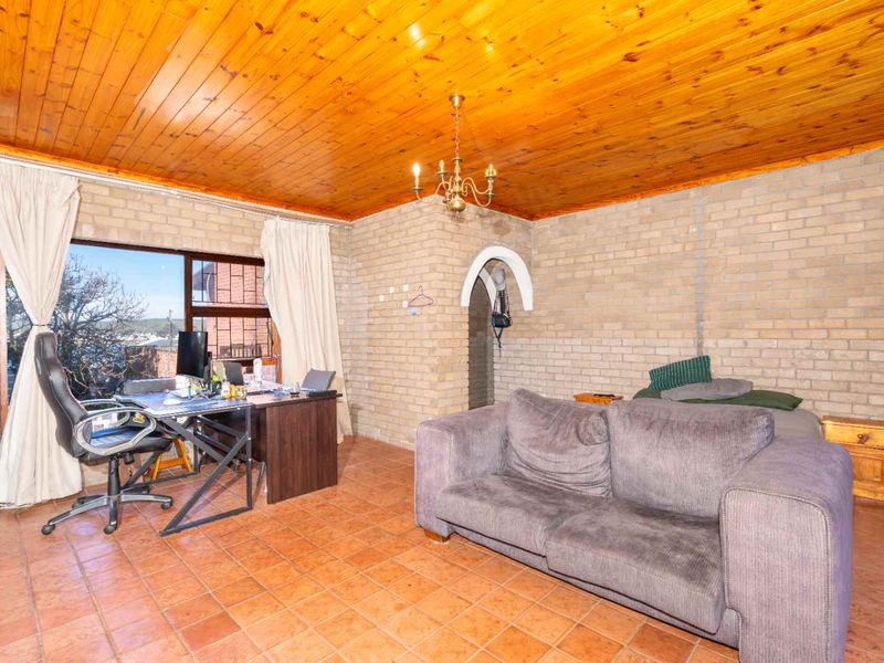 Living room featuring exposed brick walls, terracotta floor tiles, and a timber tongue and groove ceiling with a sliding door to the exterior.