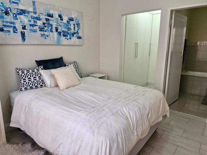 A well-maintained bedroom featuring tiled flooring, built-in cupboards, and direct access to an en-suite bathroom.