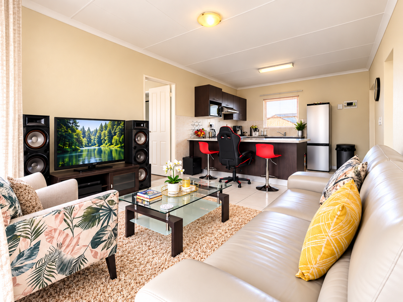 A well-maintained open-plan living and kitchen area featuring tiled flooring, a functional kitchen island, and neutral wall finishes.