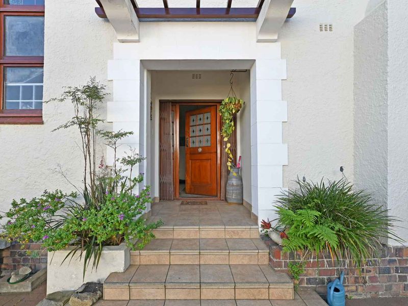 Front entrance featuring tiled steps, a timber front door with security gate, and a pergola structure over the entryway.