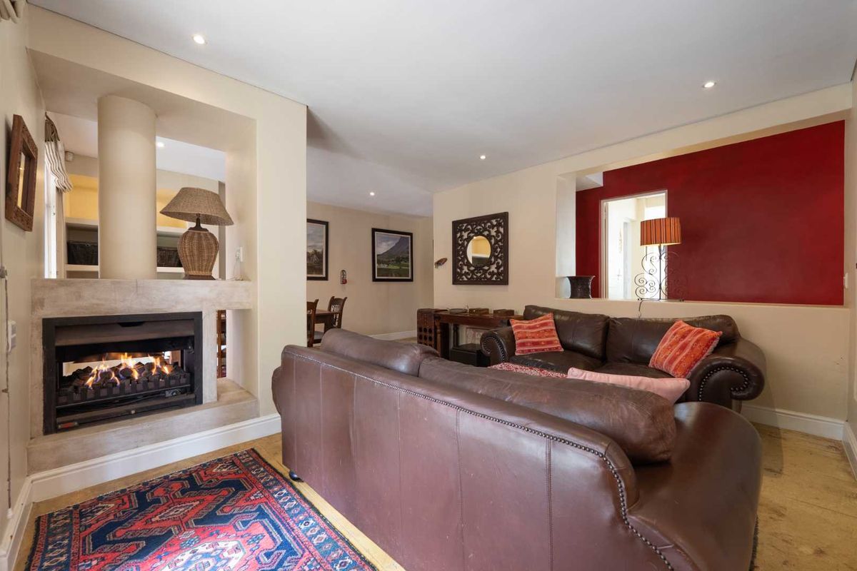 Spacious living room featuring a built-in fireplace with stone surround, recessed lighting, and an open-plan layout connecting to adjacent living areas.