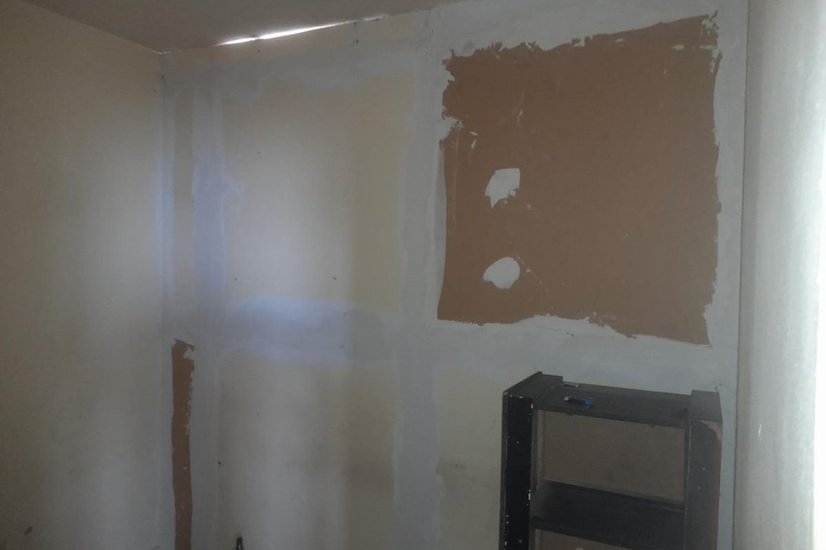 An interior room currently undergoing renovation with unfinished drywall and exposed plasterboard surfaces, requiring further wall preparation and finishing.