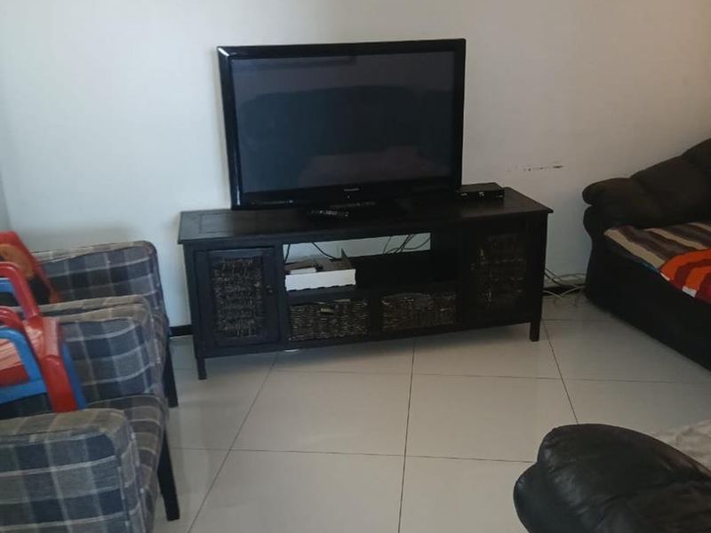 A living room area featuring neutral tiled flooring and plain walls, providing a functional space for relaxation.