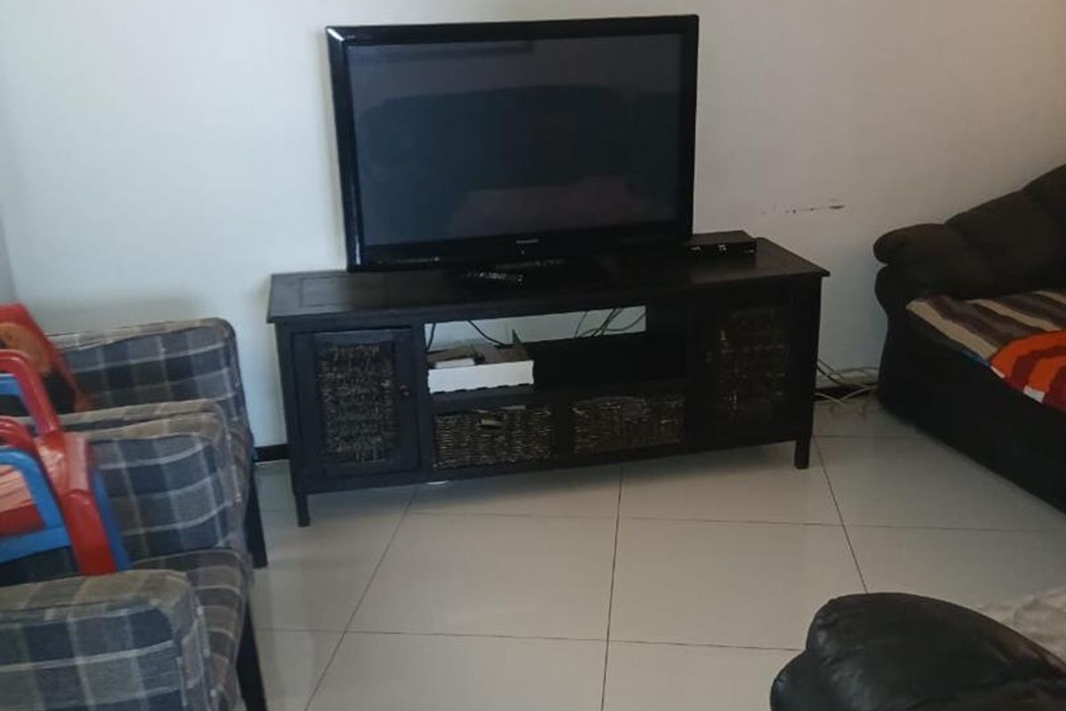 A living room area featuring neutral tiled flooring and plain walls, providing a functional space for relaxation.