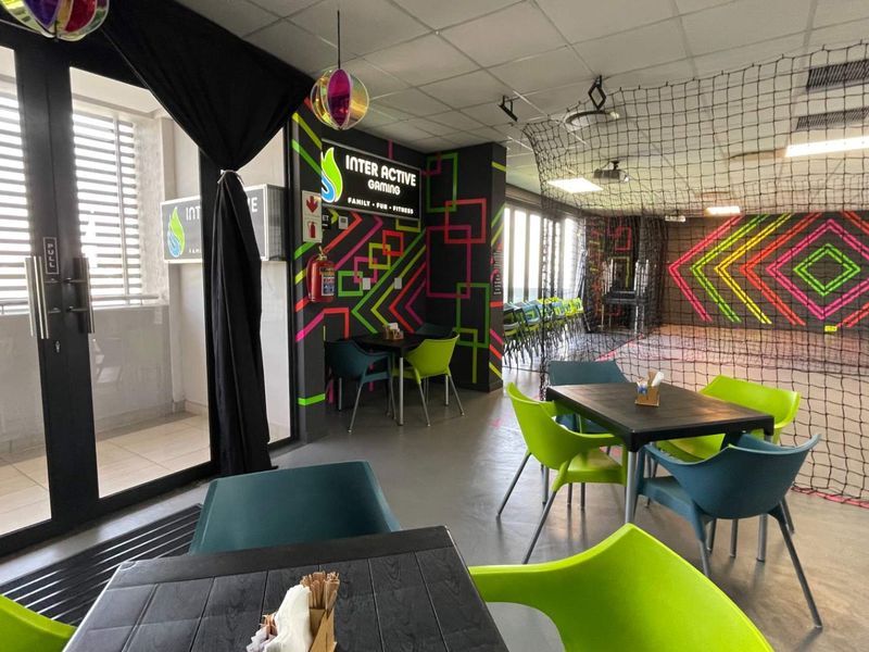 A vibrant, multi-purpose recreational space featuring modern lighting, safety netting, and direct access to an outdoor balcony area.