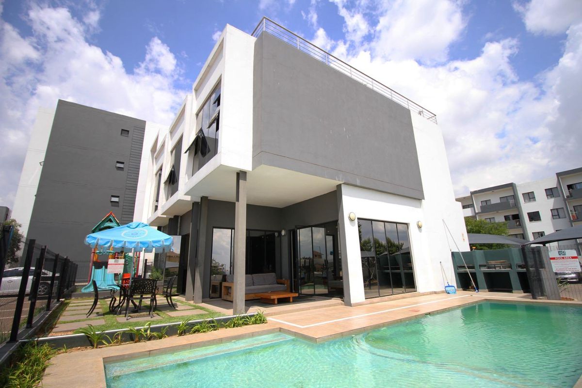 Modern two-story apartment building featuring a private swimming pool, paved patio area, and contemporary architectural design with large glass sliding doors.