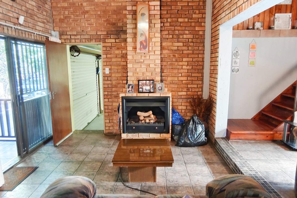 Living room featuring exposed brick walls, a built-in fireplace, tiled flooring, and an open staircase leading to the upper level.