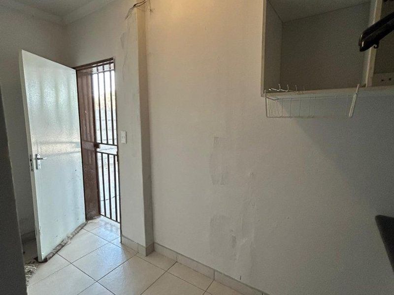 A functional utility space featuring tiled flooring, built-in shelving, and a secure exterior door access.