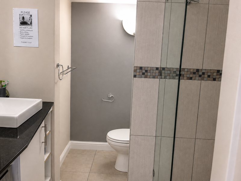 A modern bathroom featuring a vessel sink on a granite vanity, a tiled shower enclosure with glass door, and neutral wall finishes.