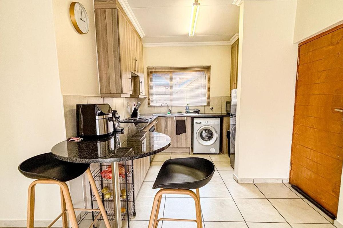 Functional kitchen featuring granite countertops, wood-look cabinetry, tiled flooring, and integrated appliances, offering a practical layout for daily meal preparation.