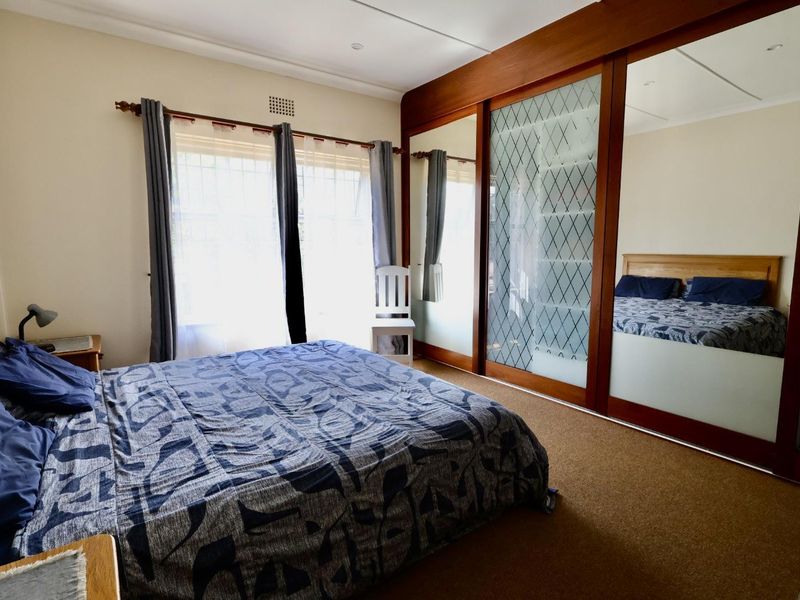 A bedroom featuring carpeted flooring and a large built-in wardrobe with mirrored and frosted glass sliding doors.
